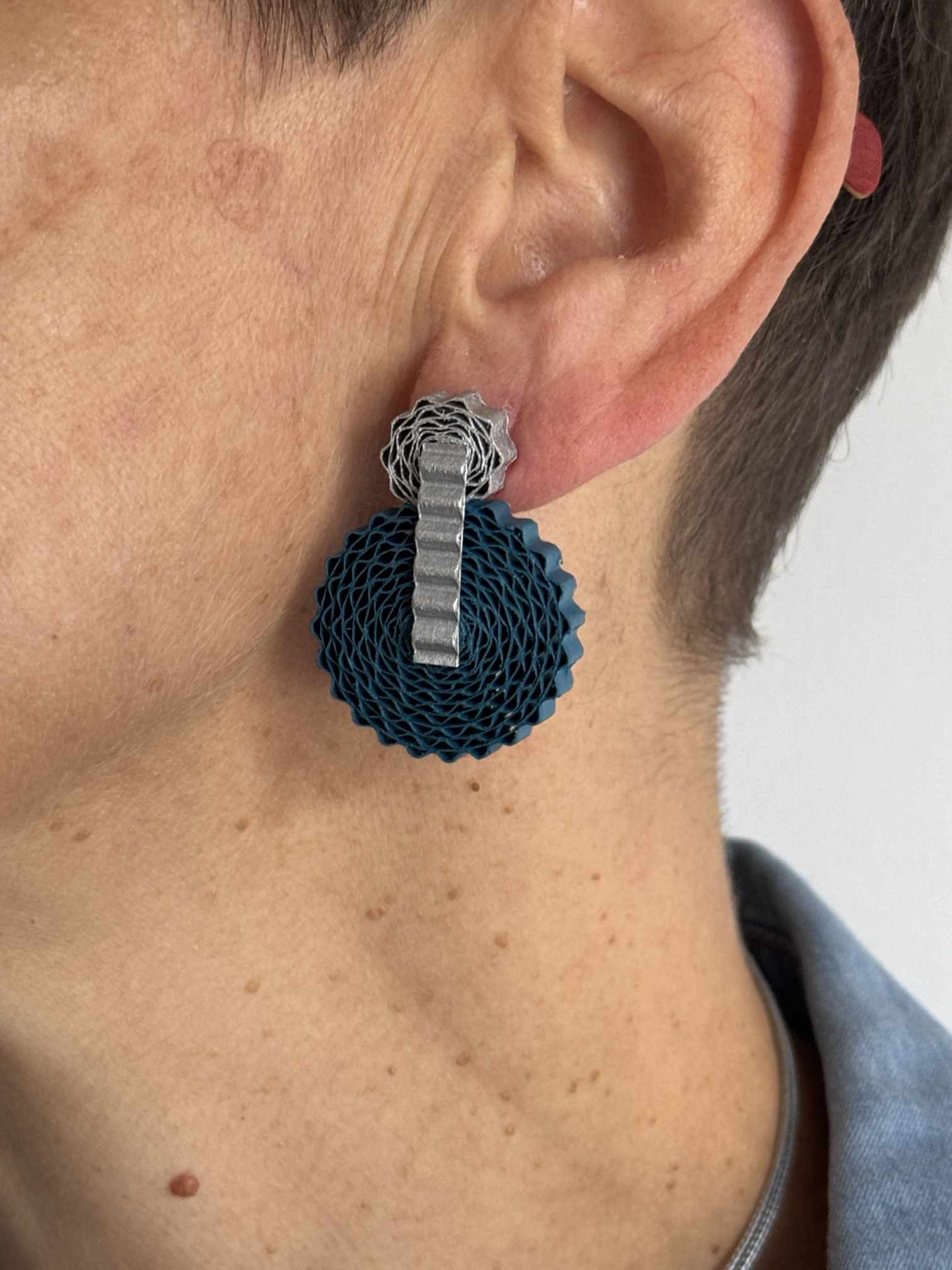 Boucles d'oreilles pendantes Rosace en carton recyclé argent et bleu, portées de profil