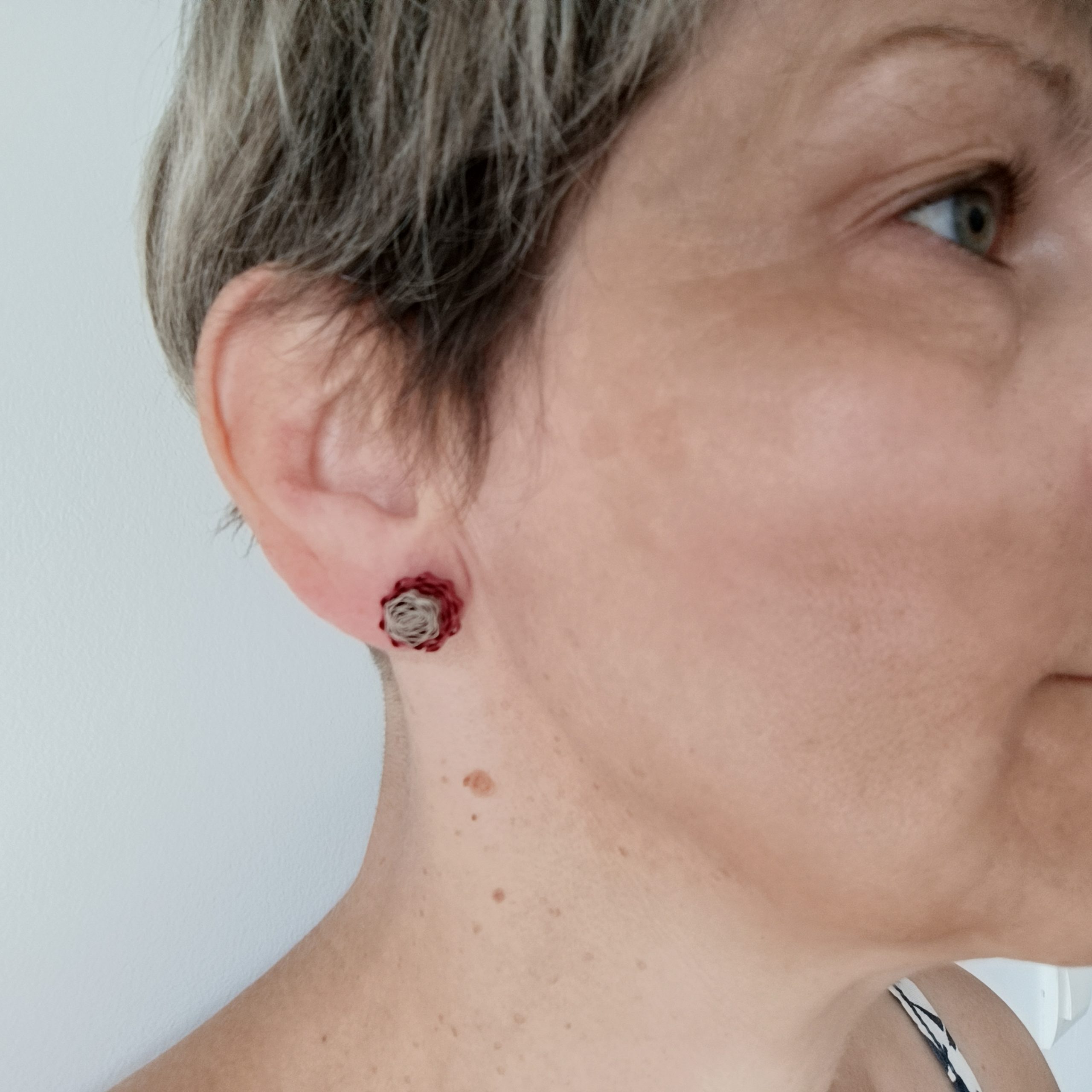 Puces d'oreilles Corolle Mini rouges en carton recyclé fabriquées à la main et portées sur l'oreille