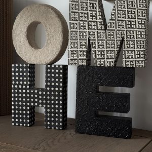 Composition originale des lettres HOME empilées en carton recyclé aux finitions variées